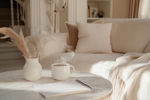 A cozy living room with a white sofa, beige pillows, and a soft blanket. On a marble coffee table are a steaming mug, a Sunday Reset Checklist in an open notebook, and a vase of dried flowers, all bathed in warm sunlight.